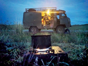 Tee wird auf einem Gaskocher zubereitet vor einem UAZ in Tuva