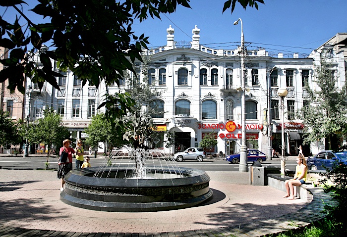 Prachtvoll verzierte Hausfassade mit einem Springbrunnen davor in Krasnoyarsk