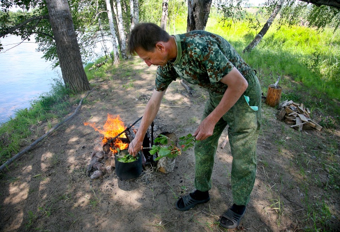 Handgepflückter Tee aus Pflanzen aus der Taiga werden über einem Lagerfeuer zubereitet